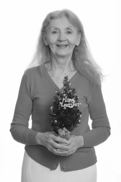 Studio shot of happy senior woman souriant tout en tenant arbre Bonne année — Photo