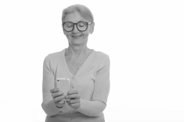 Heureuse femme nerd âgée souriante tout en utilisant le téléphone mobile — Photo