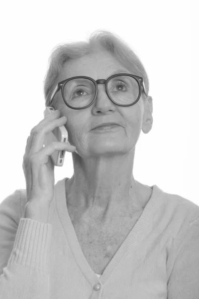 Face of senior nerd woman talking on mobile phone while thinking — Stock Photo, Image