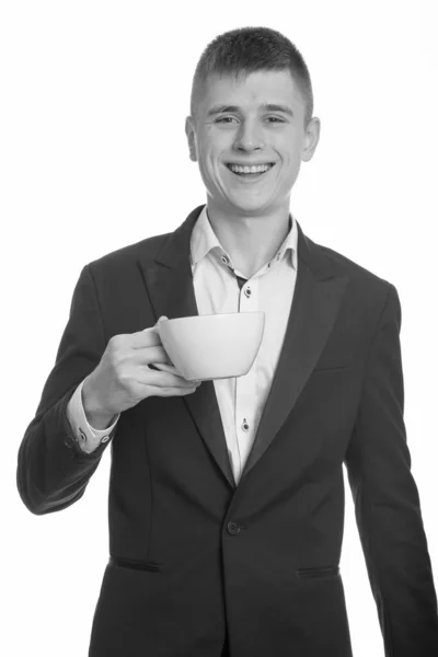 Elinde kahve fincanı tutarken gülümseyen genç işadamının stüdyo fotoğrafı. — Stok fotoğraf