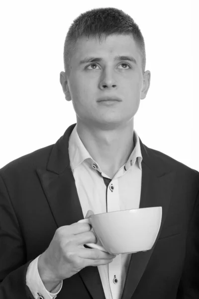 Κοντινό πλάνο του νεαρού επιχειρηματία κρατώντας φλιτζάνι καφέ, ενώ σκέφτεται — Φωτογραφία Αρχείου