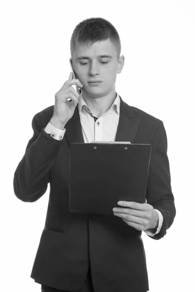 Estúdio tiro de jovem empresário falando no telefone celular enquanto lia na área de transferência — Fotografia de Stock