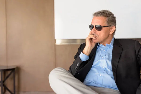 Hombre de negocios hispano maduro con gafas de sol pensando en la oficina — Foto de Stock