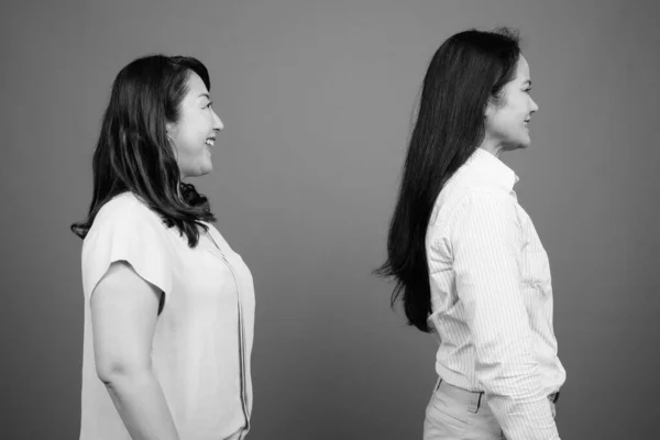 Dos mujeres de negocios asiáticas maduras juntas perfil ver estudio filmado en blanco y negro — Foto de Stock