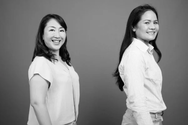 Dos maduras empresarias asiáticas juntas estudio filmado en blanco y negro — Foto de Stock