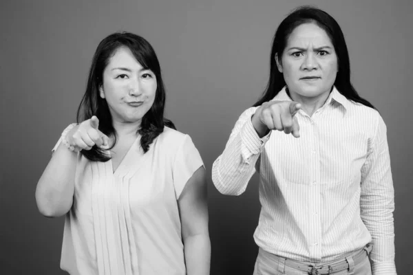 Dos mujeres de negocios asiáticas maduras juntas señalando con el dedo enojado — Foto de Stock