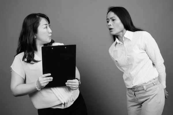 Dos mujeres de negocios asiáticas maduras juntas buscando documentos — Foto de Stock