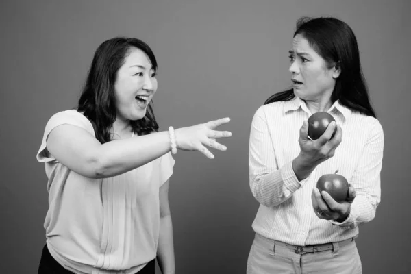 Dos maduras empresarias asiáticas junto con manzanas en estudio — Foto de Stock