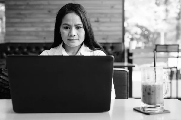Rijpere Aziatische zakenvrouw met behulp van laptop computer in coffeeshop — Stockfoto