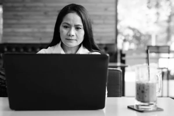Rijpere Aziatische zakenvrouw met behulp van laptop computer in coffeeshop — Stockfoto