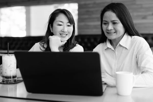 Twee volwassen Aziatische vrouwen met behulp van laptop computer bij coffeeshop — Stockfoto