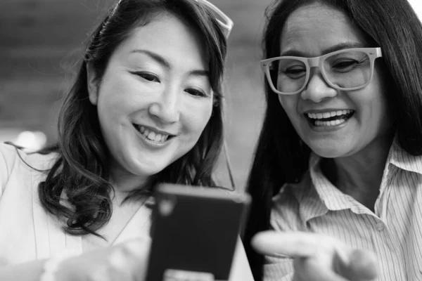 Twee volwassen Aziatische vrouwen samen opknoping uit in de coffeeshop terwijl het hebben van plezier — Stockfoto