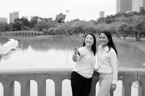 셀카 스틱을 사용하여 셀카를 복용하는 두 명 의성인 아시아 여성 — 스톡 사진