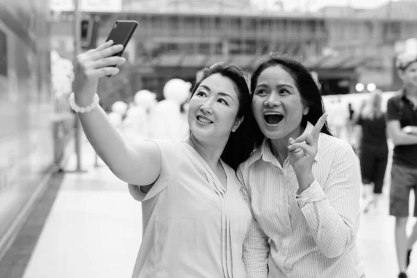 Two mature Asian women together taking selfie with mobile phone — Stock Photo, Image