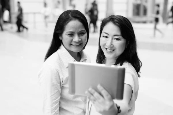 Twee volwassen Aziatische vrouwen samen met behulp van digitale tablet computer — Stockfoto