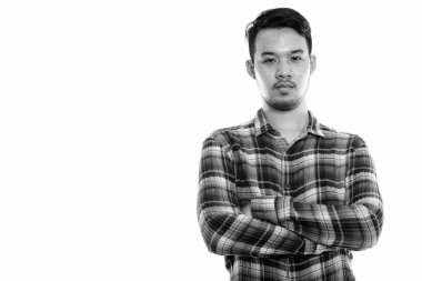 Kollarını kavuşturmuş genç Asyalı adamın stüdyo fotoğrafı.