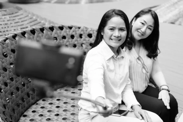 셀카 스틱을 부착 한 휴대 전화로 셀카를 복용하는 행복 한 여성들 — 스톡 사진