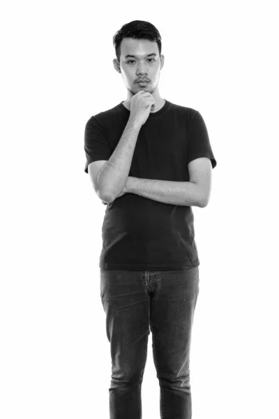 Studioaufnahme eines jungen asiatischen Mannes, der beim Denken steht — Stockfoto