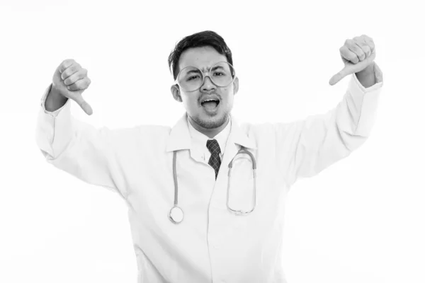 Studio shot de jeune en colère asiatique homme médecin donnant pouces vers le bas — Photo