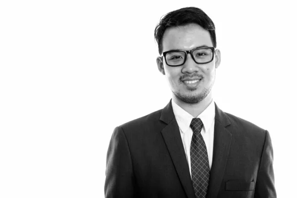 Studio shot van jong gelukkig aziatisch zakenman glimlachen terwijl het dragen van bril — Stockfoto