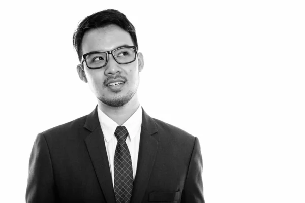 Estudio de tiro de joven feliz empresario asiático sonriendo y usando gafas mientras pensaba —  Fotos de Stock