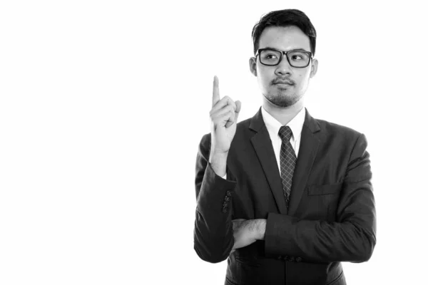 Studioaufnahme eines jungen asiatischen Geschäftsmannes, der beim Denken mit dem Finger nach oben zeigt — Stockfoto