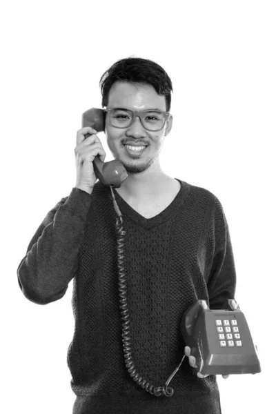 Stúdió lövés fiatal boldog ázsiai férfi mosolyog, miközben beszél a régi telefon — Stock Fotó