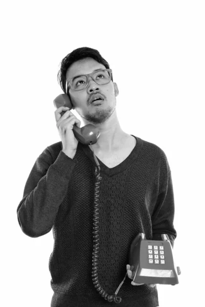 Stúdió lövés fiatal ázsiai férfi beszél a régi telefon, miközben gondolkodás — Stock Fotó