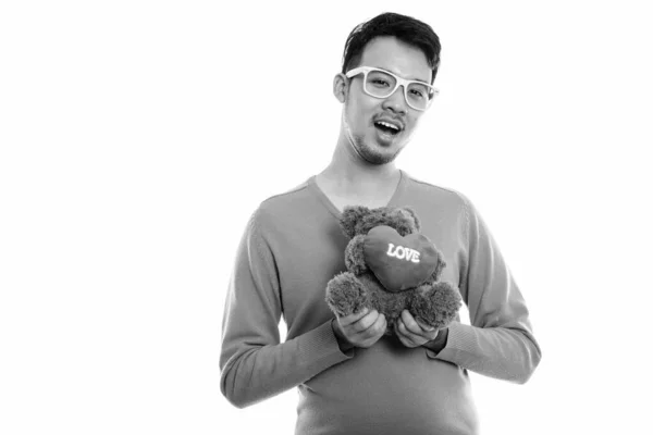 Зйомки молодого щасливого азіатського чоловіка, який посміхається, тримаючи Тедді ведмедя з серцем і любовним знаком. — стокове фото
