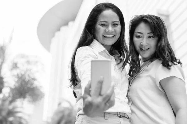 Dos mujeres asiáticas maduras tomando selfie con teléfono móvil — Foto de Stock