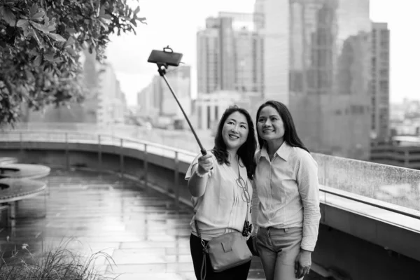 Азиатские женщины делают селфи с помощью мобильного телефона, прикрепленного к селфи-палочке — стоковое фото