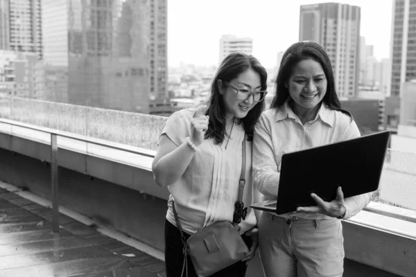 Dos mujeres asiáticas maduras juntas contra la vista de la ciudad — Foto de Stock