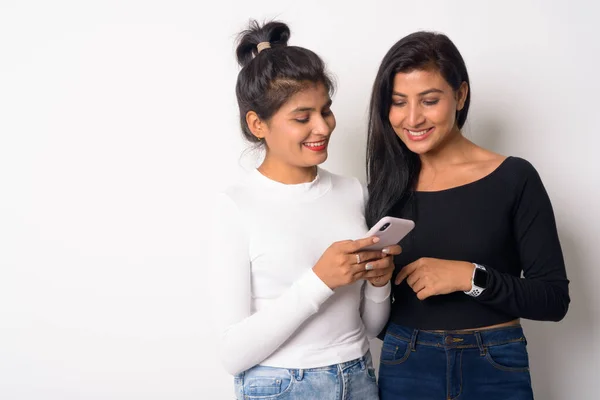 Two happy young beautiful Persian women using phone together