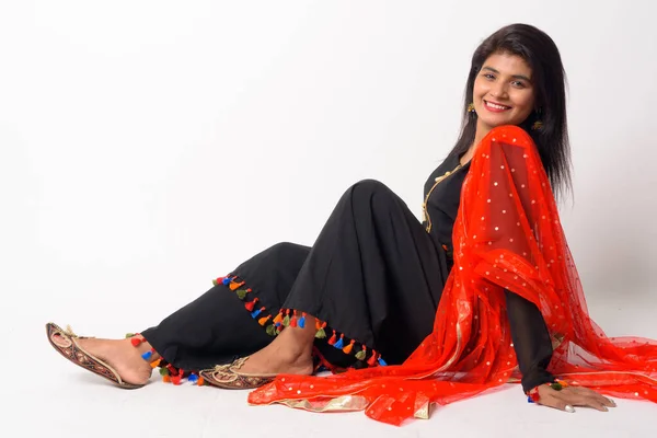 Full body shot di felice giovane donna persiana seduta sul pavimento in abiti tradizionali — Foto Stock