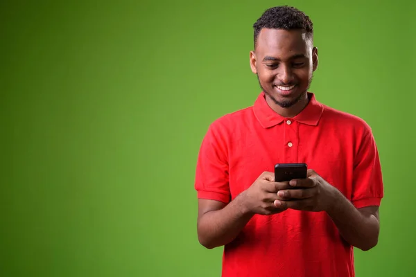 Young handsome African man against green background — Stock Photo, Image