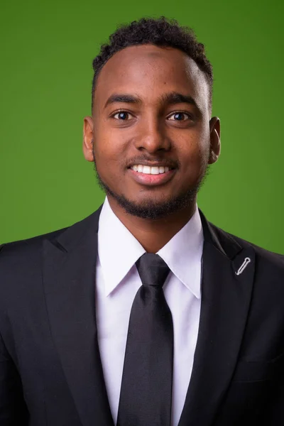 Young handsome African businessman against green background
