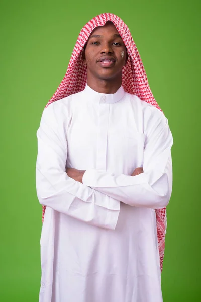 Junger afrikanischer Mann in traditioneller muslimischer Kleidung gegen gre — Stockfoto