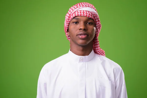 Young African man wearing traditional Muslim clothes against gre — Stock Photo, Image