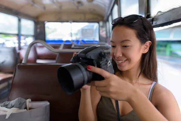 Jeune touriste assise à bus tout en utilisant un appareil photo reflex numérique — Photo