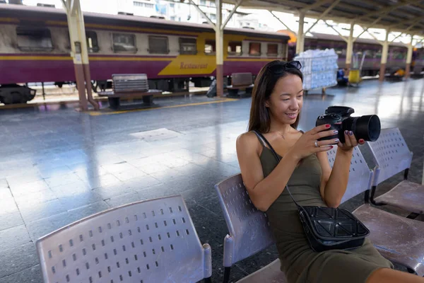 Молодая туристка сидит и пользуется камерой DSLR — стоковое фото