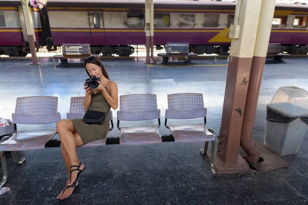 Jeune femme touristique assise et utilisant un appareil photo reflex numérique — Photo