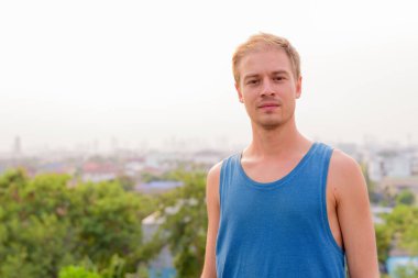 Sarışın, açık havada dinlenen yakışıklı genç bir adam.