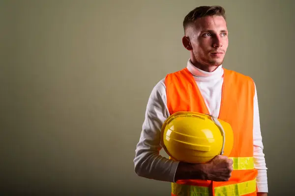 Joven trabajador de la construcción contra fondo de color —  Fotos de Stock