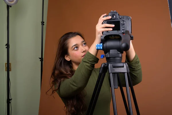 Young beautiful Indian woman vlogging against brown background — Stock Photo, Image