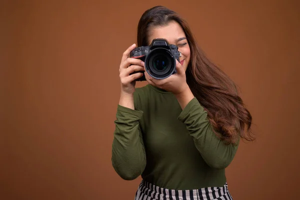 Jong mooi indiaans vrouw met camera tegen bruin backgroun — Stockfoto