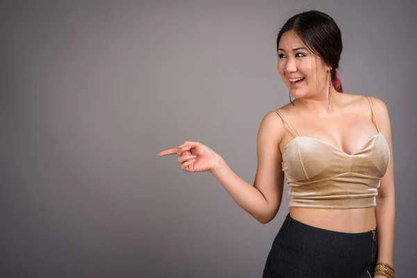 Junge schöne asiatische Frau vor grauem Hintergrund — Stockfoto