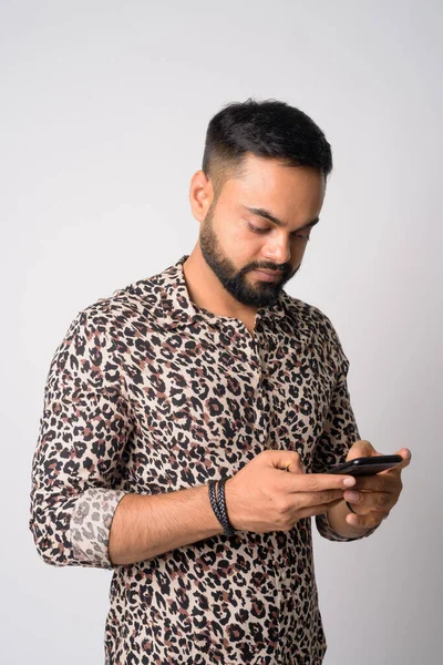 Portrait of young handsome bearded Indian man using phone — Stock Photo, Image