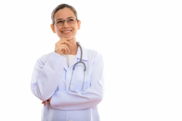 Estúdio tiro de jovem mulher feliz médico sorrindo e pensando whi — Fotografia de Stock