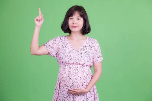 Retrato de bela mulher grávida asiática apontando para cima — Fotografia de Stock