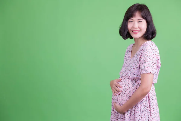 Profiel weergave van gelukkig aziatische zwangere vrouw op zoek naar camera — Stockfoto